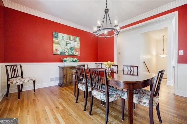 dining room with visible vents, an inviting chandelier, ornamental molding, light wood-type flooring, and baseboards