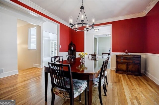 dining space with a notable chandelier, ornamental molding, and light wood-style floors