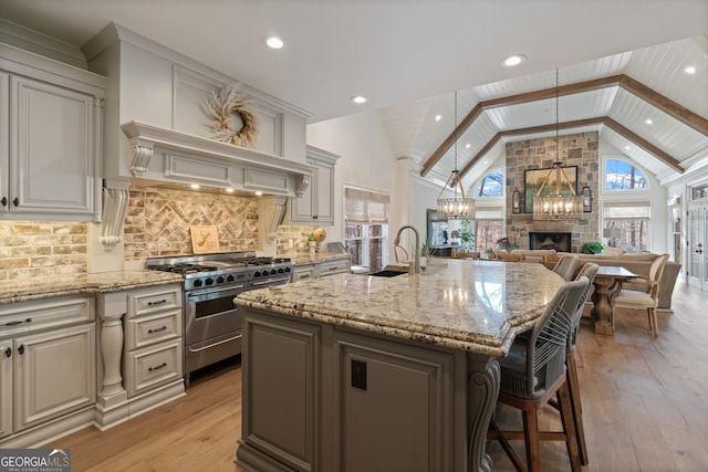 kitchen with light stone countertops, high end stainless steel range oven, high vaulted ceiling, and a sink