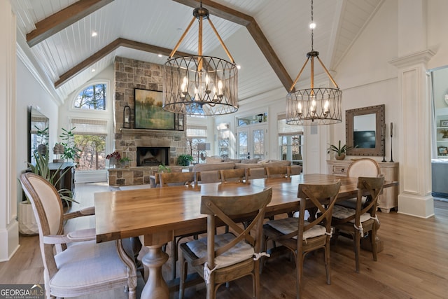 dining room with high vaulted ceiling, a fireplace, a chandelier, and wood finished floors