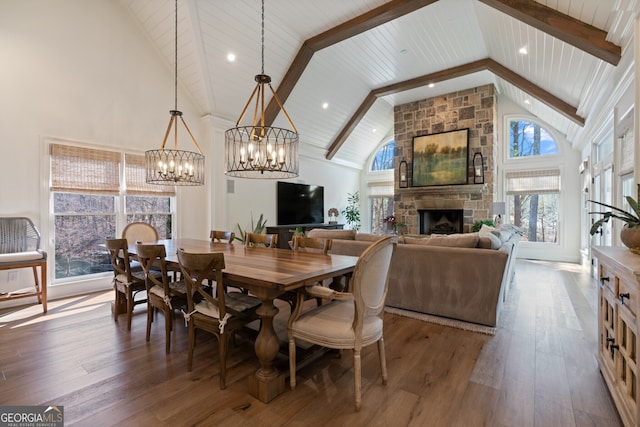 dining space with high vaulted ceiling, wood-type flooring, a fireplace, and beam ceiling