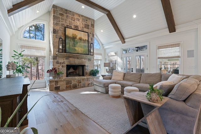 living area featuring high vaulted ceiling, french doors, a fireplace, and hardwood / wood-style flooring