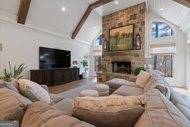 living room featuring light wood-style floors, beamed ceiling, a stone fireplace, and high vaulted ceiling