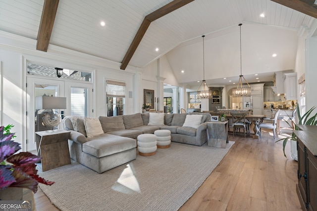 living area with high vaulted ceiling, beam ceiling, light wood-style flooring, and an inviting chandelier