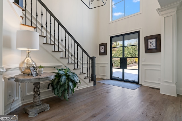 foyer with stairs, a wealth of natural light, a decorative wall, and wood finished floors