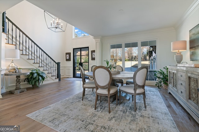 dining room with wainscoting, stairway, ornamental molding, wood finished floors, and a decorative wall