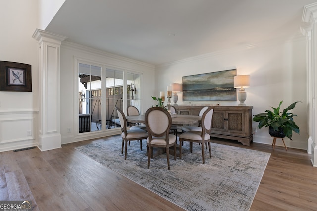 dining space with baseboards, ornamental molding, wood finished floors, and ornate columns