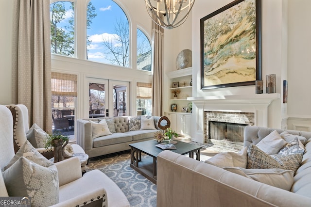 living area with built in shelves, a healthy amount of sunlight, a fireplace, and a towering ceiling