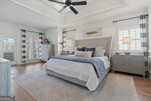 bedroom with ceiling fan, a tray ceiling, crown molding, and wood finished floors