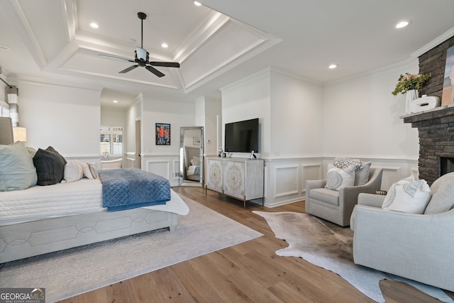 bedroom with a fireplace, recessed lighting, ornamental molding, wainscoting, and wood finished floors