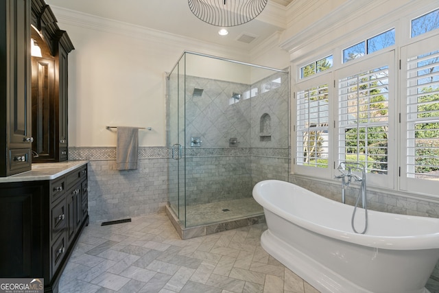 full bathroom featuring ornamental molding, a soaking tub, a shower stall, and tile walls