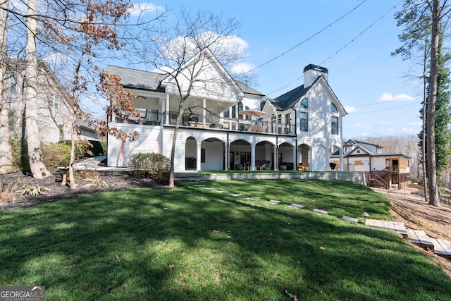 rear view of house featuring a balcony, a chimney, and a lawn