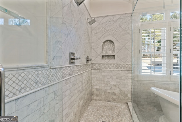 bathroom featuring a tile shower, tile walls, and a freestanding bath