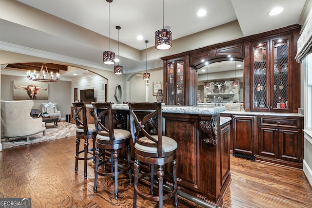 bar with arched walkways, ornamental molding, wood finished floors, and decorative light fixtures