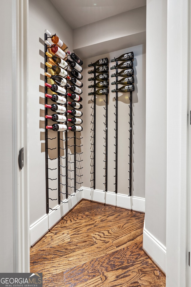 wine area with baseboards and wood finished floors