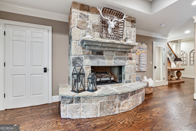 living room with a stone fireplace, stairway, wood finished floors, and crown molding