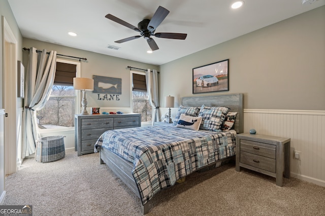 carpeted bedroom featuring a wainscoted wall, multiple windows, visible vents, and recessed lighting