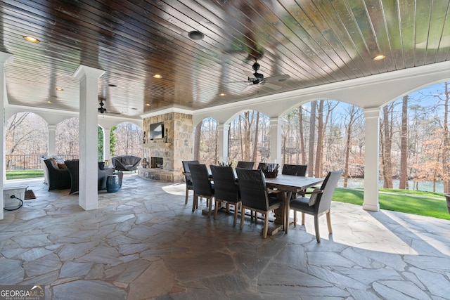 view of patio featuring ceiling fan, an outdoor stone fireplace, and outdoor dining area