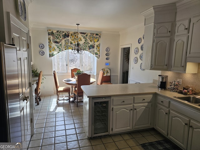 kitchen with wine cooler, a peninsula, hanging light fixtures, light countertops, and a sink