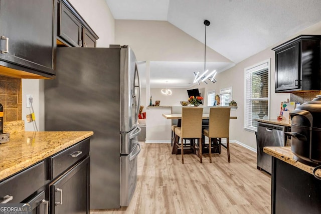 kitchen with light wood finished floors, lofted ceiling, hanging light fixtures, light stone countertops, and stainless steel appliances