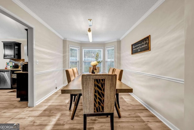 dining area with ornamental molding, light wood-style flooring, and a textured ceiling