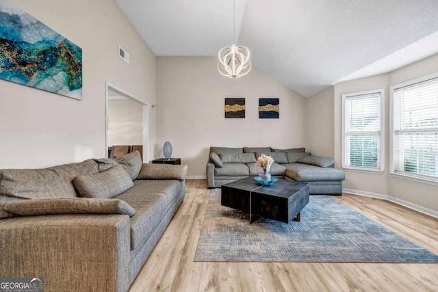 living room featuring light wood finished floors, baseboards, vaulted ceiling, and a chandelier