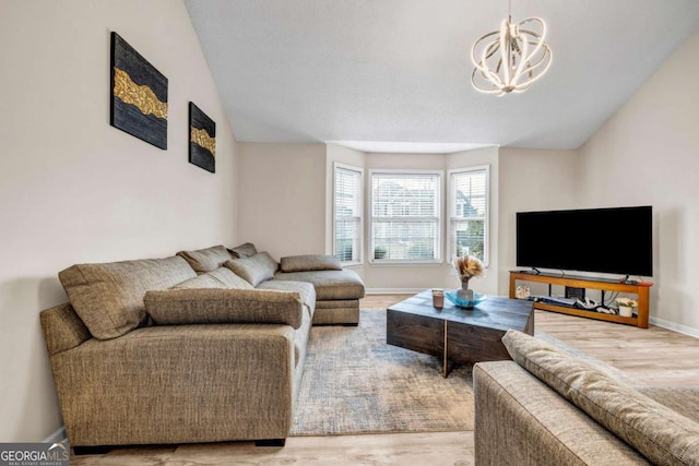 living area featuring a notable chandelier, vaulted ceiling, and wood finished floors