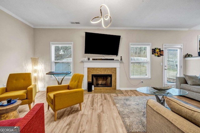 living area with a healthy amount of sunlight, a fireplace, visible vents, and wood finished floors