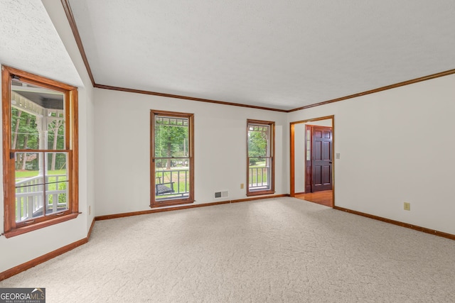 empty room featuring a textured ceiling, light carpet, visible vents, baseboards, and ornamental molding