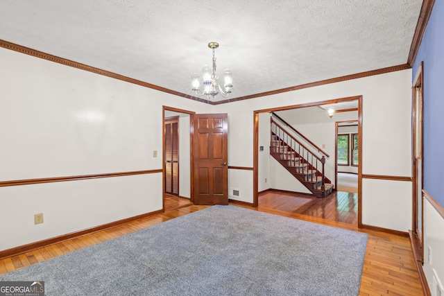 unfurnished room featuring visible vents, ornamental molding, a textured ceiling, light wood-style floors, and a chandelier