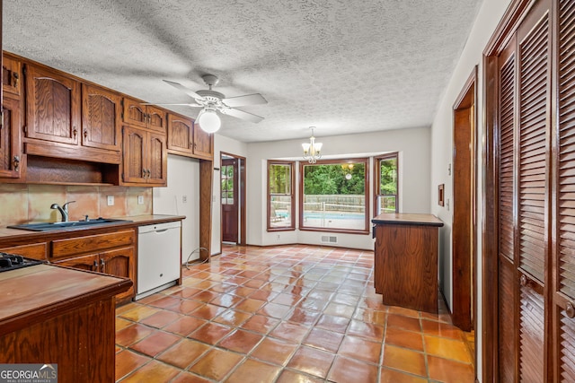 kitchen featuring visible vents, dark countertops, white dishwasher, pendant lighting, and a sink