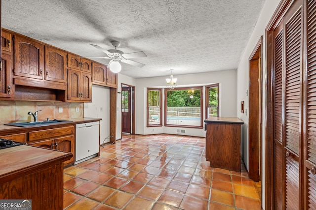 kitchen featuring a sink, backsplash, dishwasher, ceiling fan with notable chandelier, and visible vents