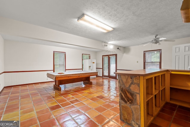 game room featuring light tile patterned floors, a ceiling fan, wainscoting, pool table, and a textured ceiling