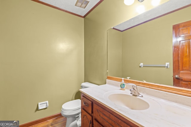 bathroom featuring a textured ceiling, toilet, vanity, visible vents, and ornamental molding