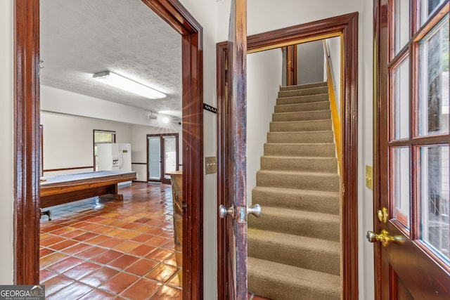 staircase with a textured ceiling and tile patterned flooring