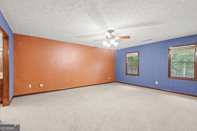 empty room with light carpet, baseboards, visible vents, and a textured ceiling