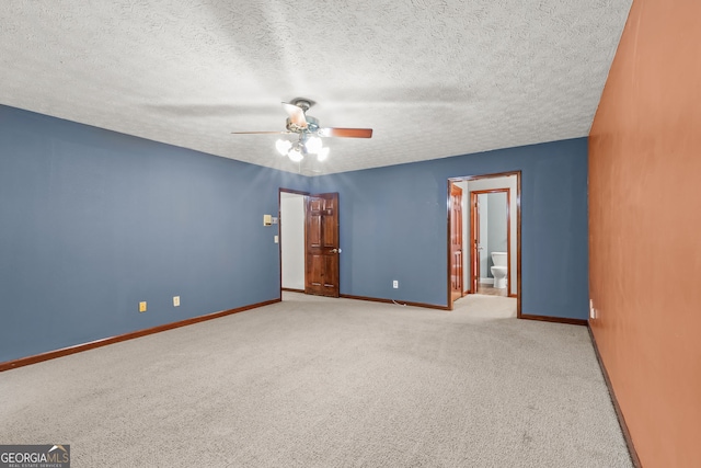 empty room with light colored carpet, ceiling fan, a textured ceiling, and baseboards