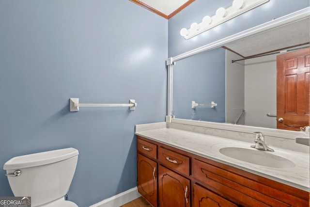 bathroom featuring toilet, baseboards, crown molding, and vanity