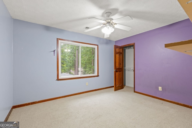 spare room featuring light carpet, visible vents, baseboards, and a textured ceiling