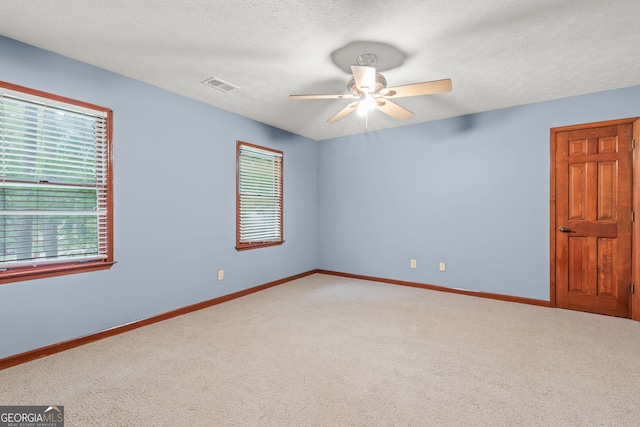 spare room with ceiling fan, visible vents, carpet, and plenty of natural light
