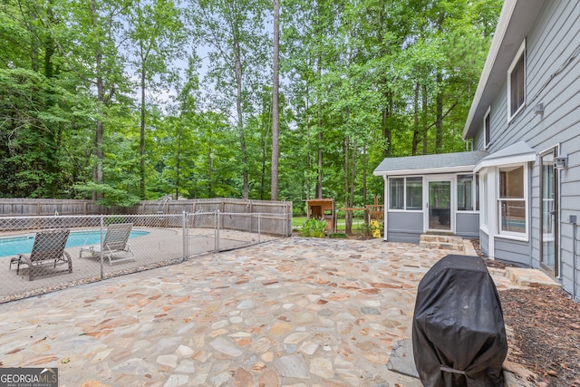 view of patio / terrace featuring entry steps, a fenced in pool, area for grilling, a sunroom, and a fenced backyard