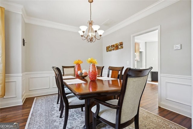 dining area featuring a wainscoted wall, crown molding, a chandelier, and dark wood-style flooring