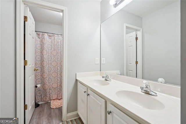 bathroom featuring wood finished floors, a sink, and double vanity