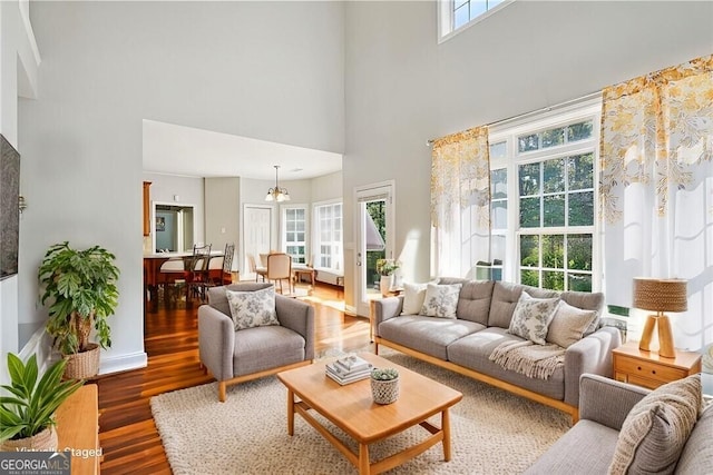 living room with dark wood-type flooring, a chandelier, and a healthy amount of sunlight