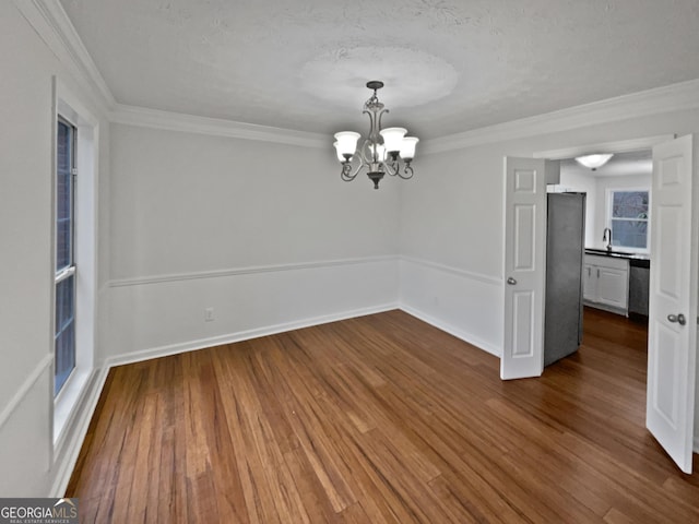 spare room featuring ornamental molding, dark wood-style flooring, and a notable chandelier