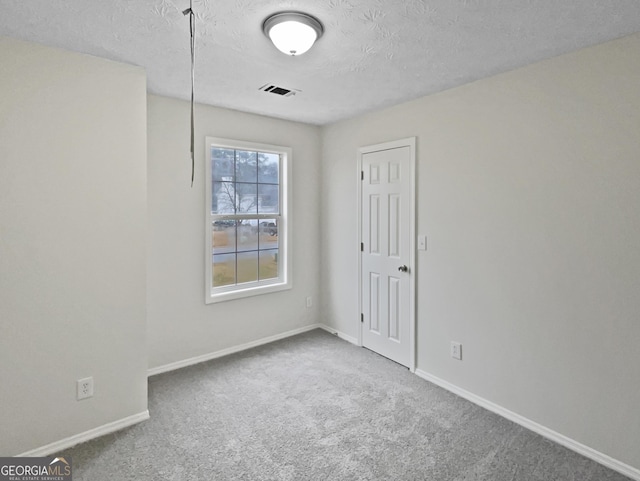 carpeted empty room with a textured ceiling, visible vents, and baseboards