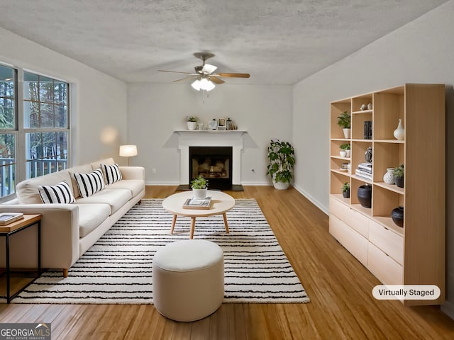 living room featuring light wood finished floors, a fireplace with flush hearth, and baseboards