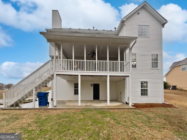 back of property with a ceiling fan, a patio area, a yard, and stairway