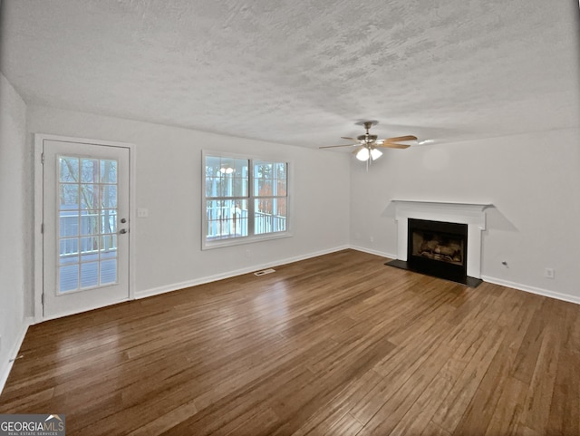 unfurnished living room with a fireplace with raised hearth, dark wood-style flooring, and visible vents