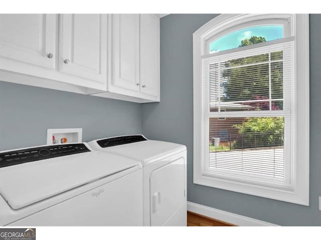 clothes washing area featuring cabinet space, washing machine and clothes dryer, a wealth of natural light, and baseboards